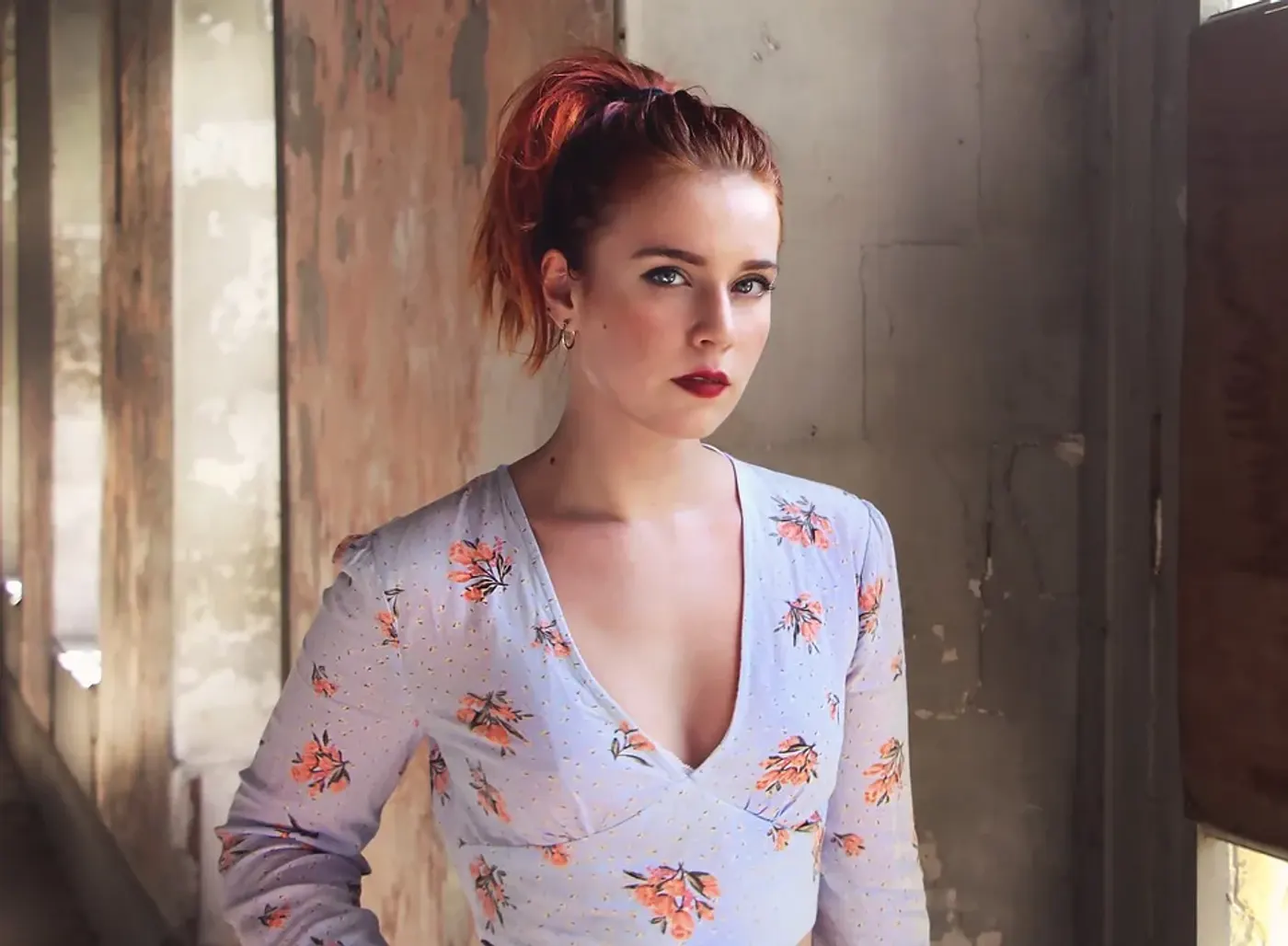Personne aux cheveux roux appliquant un fard brun rosé sur sa paupière avec un pinceau