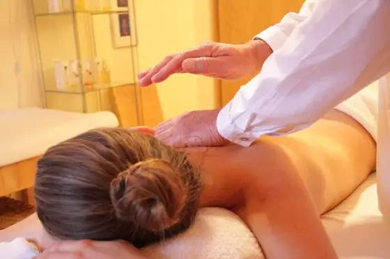 Cabine de massage lumineuse avec table recouverte d’un drap blanc, huile et serviettes pliées