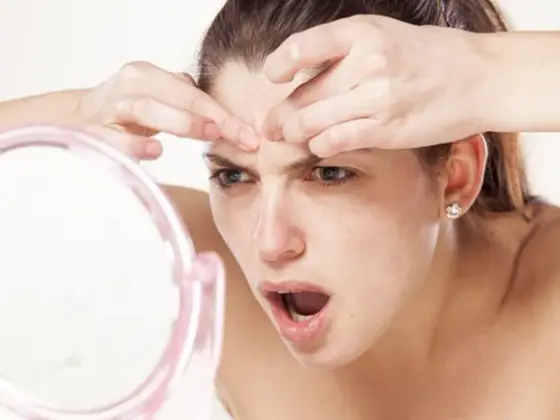 Flacons de soin visage, patchs hydrocolloïdes et miroir posés sur une serviette claire