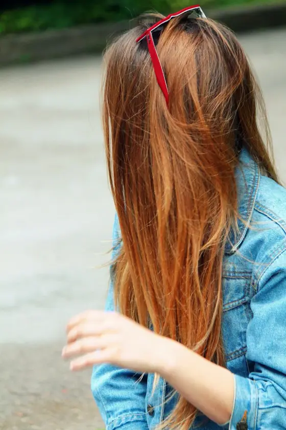Personne séchant ses cheveux avec un sèche-cheveux tenu à distance devant un miroir