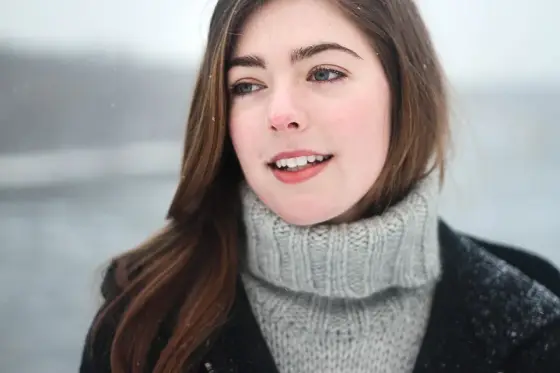 Produits de soin d’hiver, serviette et crème posés près d’un lavabo lumineux