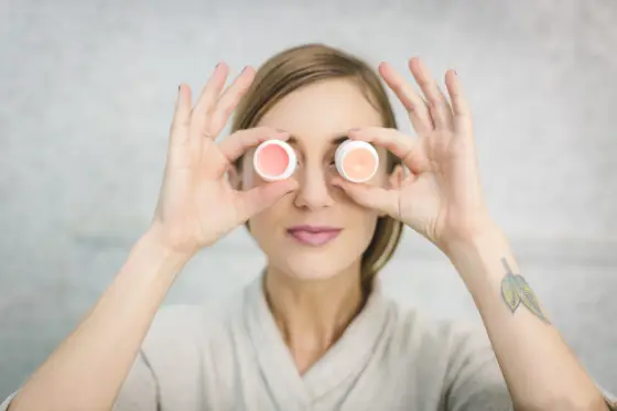Personne appliquant une crème légère sur sa joue devant un miroir dans une salle de bain lumineuse