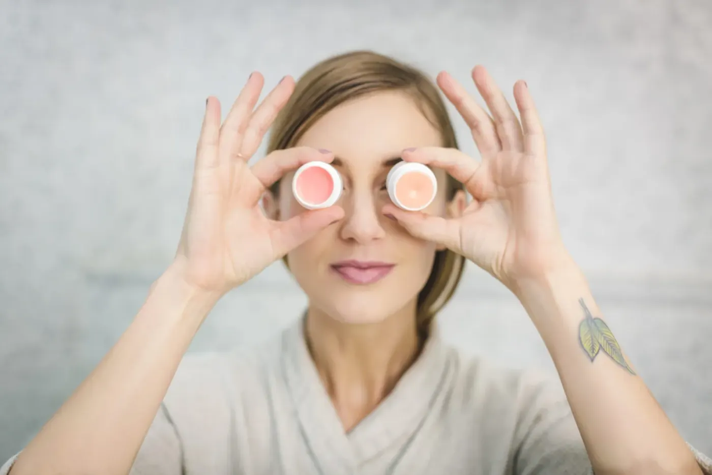 Personne appliquant une crème légère sur sa joue devant un miroir dans une salle de bain lumineuse